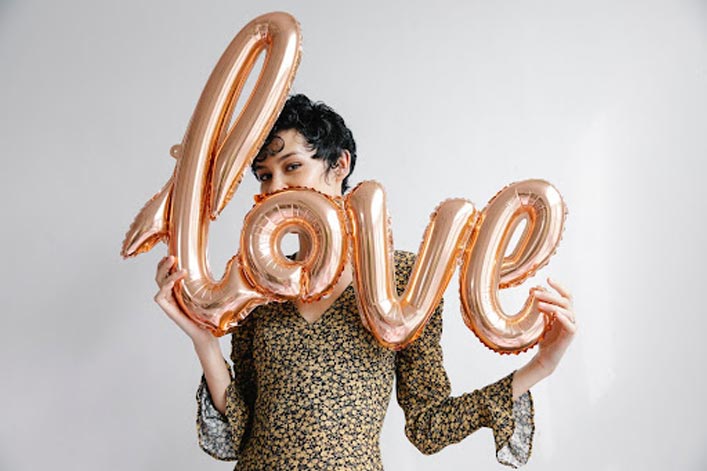 woman holding a balloon that spells l-o-v-e