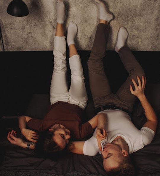 A photo of a couple lying on a bed.